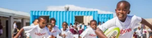 Wide crop of smiling children outside a blue container building