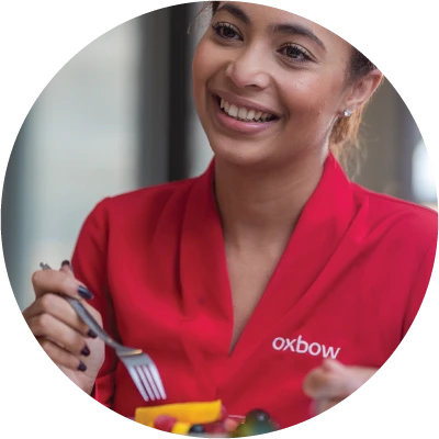 Smiling Oxbow staff member in red serving breakfast