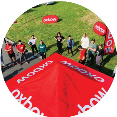 Oxbow staff celebrating at an outdoor event behind an Oxbow banner